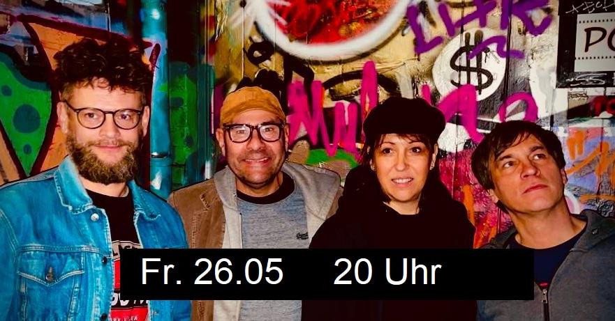 Foto der Band „ADHS konform“ – eine junge Frau und drei Männer, zwei im mittleren Alter – vor einer Wand mit vielen Graffiti, offenbar eine Konzertlocation; davor der Text „Freitag, 26. Mai, 20:00 Uhr“